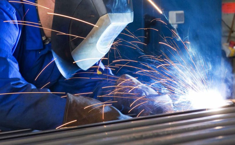 A welding machine operator uses a MIG gun to perform a weld using metal-cored wire.