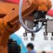 An orange collaborative robot (cobot) prepares to pick up equipment to aid in the manufacturing process.