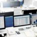 A row of desktop computers display organized data in various formats.