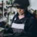 Torch in hand, a welder prepares her workpiece in an industrial shop.